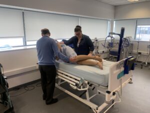 Care staff practising repositioning a person in a profiling bed during a moving and handling training session