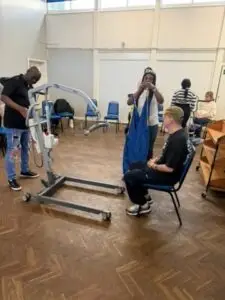 Caregivers training with a patient hoist and sling.- Care Handling